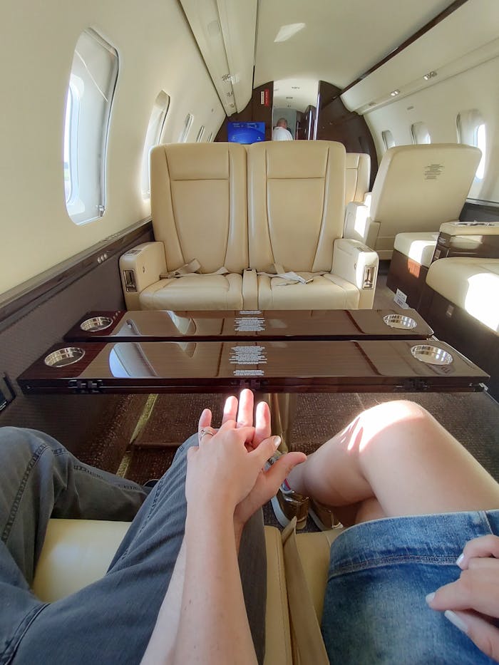 Couple holding hands inside a luxurious private jet with elegant leather seating.